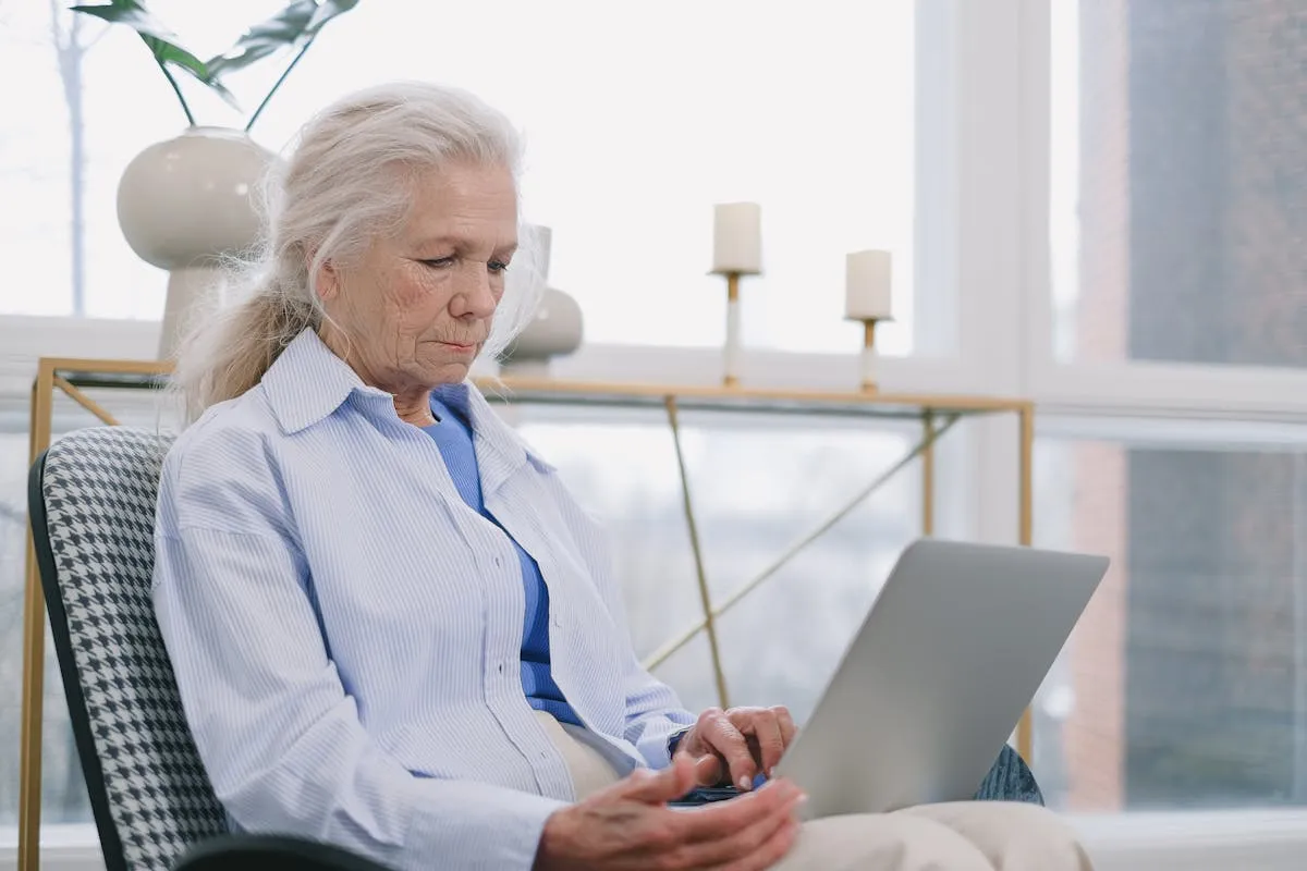 A senior woman comfortably comparing insurance plans on a laptop at home